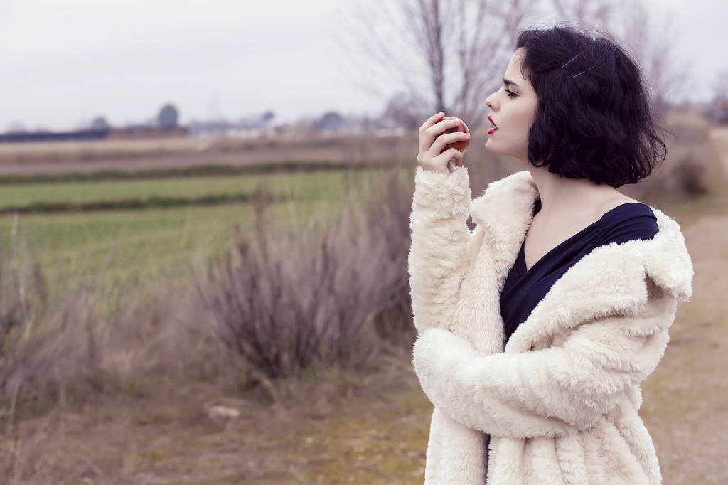 Mujer mirando una manzana roja en medio de un campo.