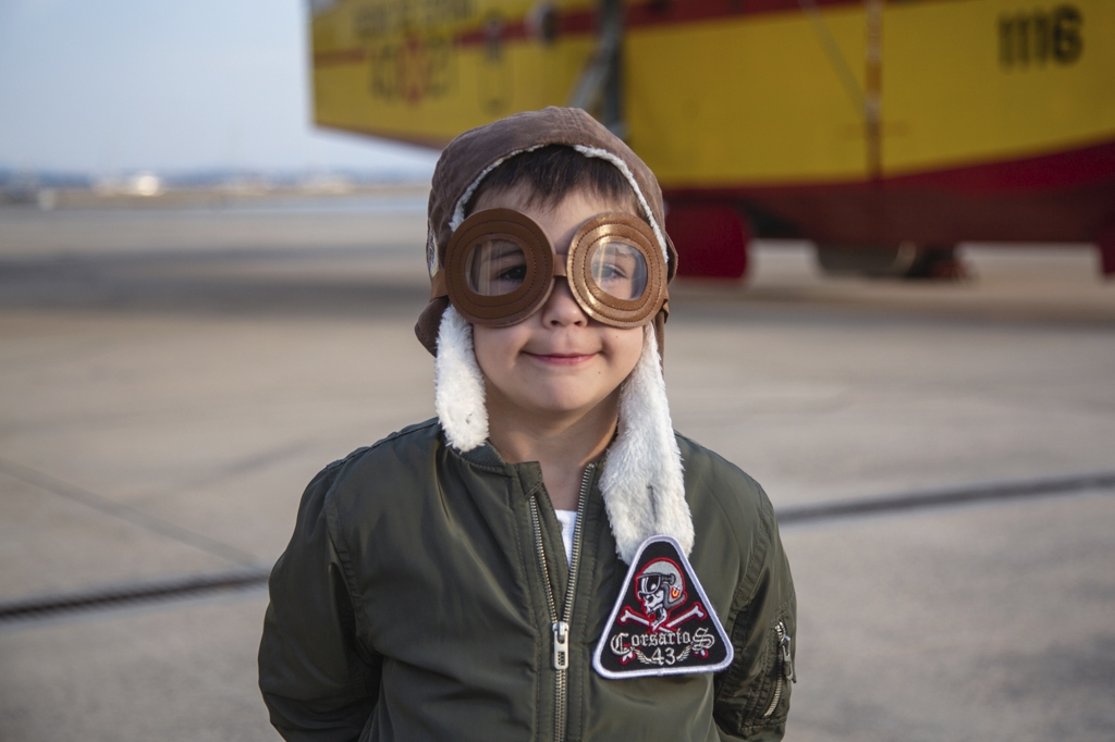Niño disfrazado deRetrato de un niño disfrazado de aviador cerca de un hidroavión amarillo en Mallorca.