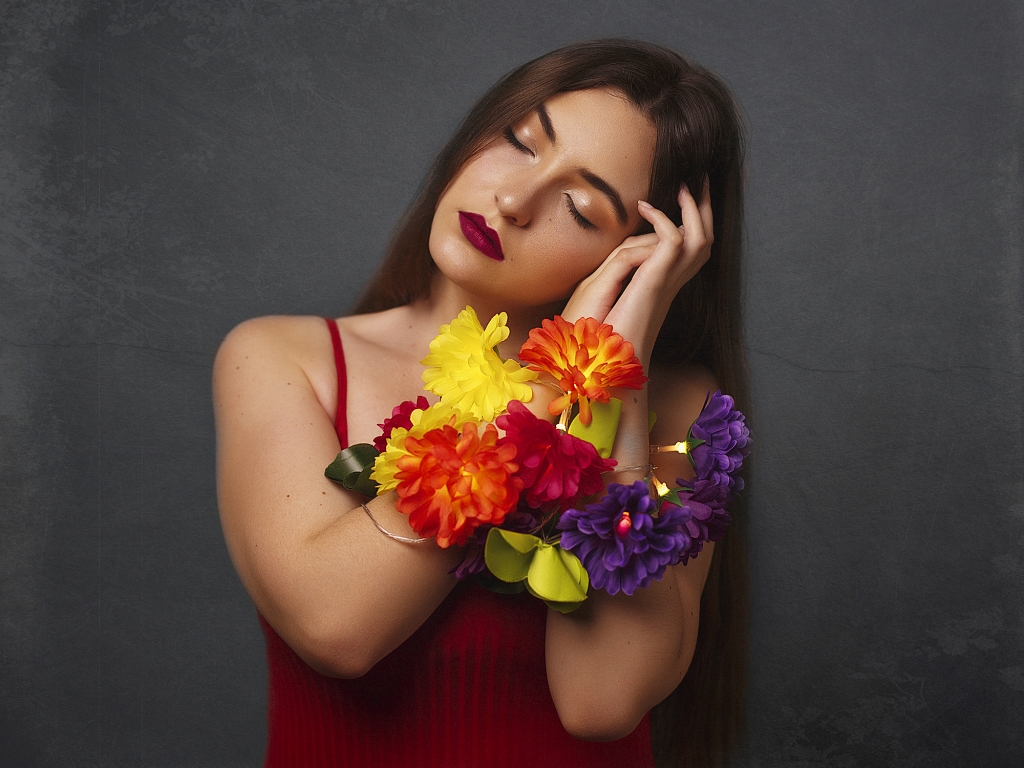 Mujer con los ojos cerrados y con las manos unidas por una guirnalda de flores.
