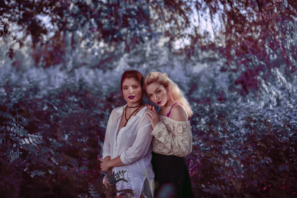 Dos mujeres abrazadas en medio de un sombrío bosque.
