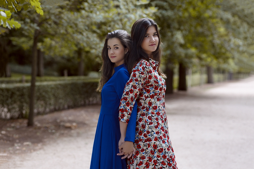Dos hermanas de pelo largo cogidas de la mano en un parque.