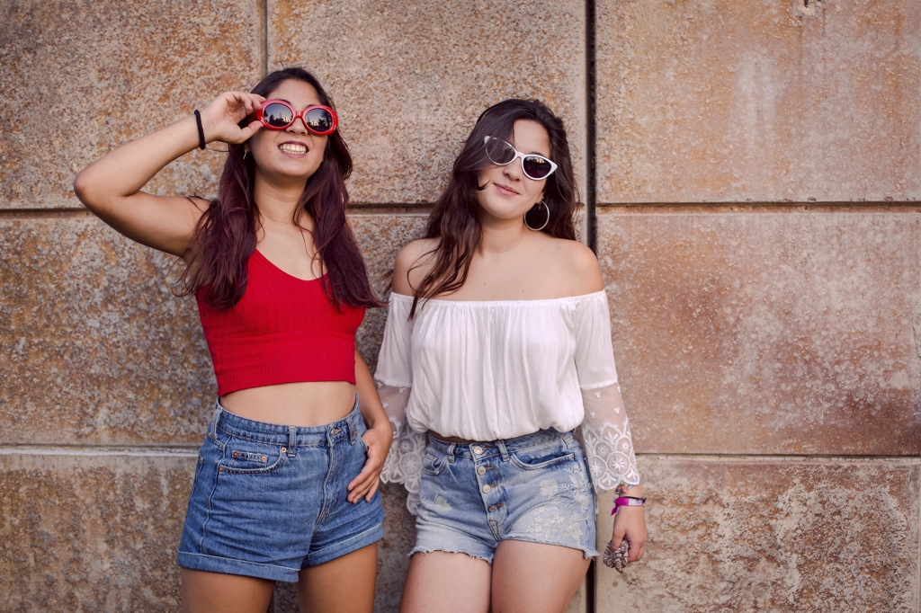 Hermanas divertidas con gafas de sol de colores en el parque.
