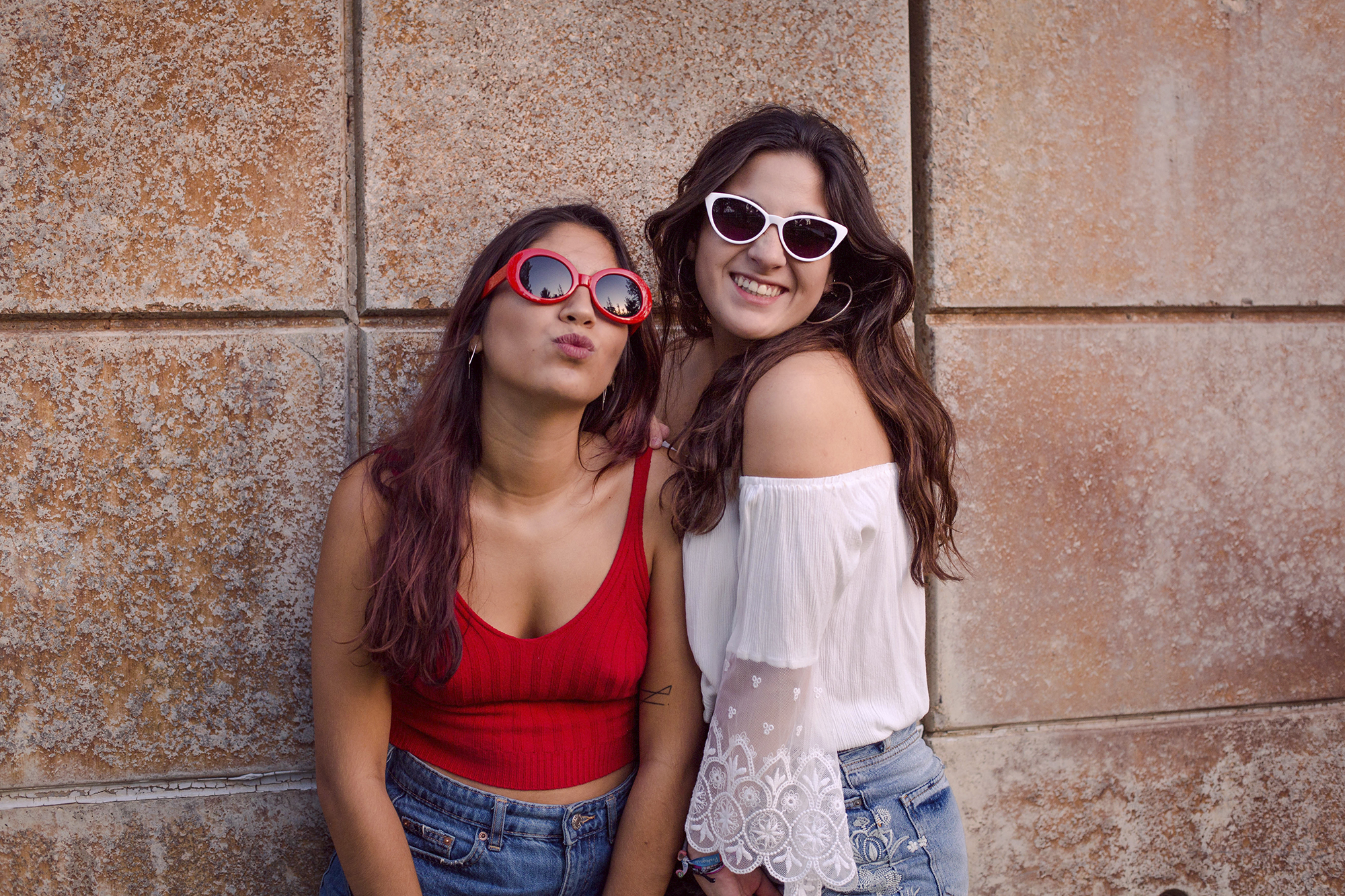Hermanas divertidas con gafas de sol de colores en el parque.