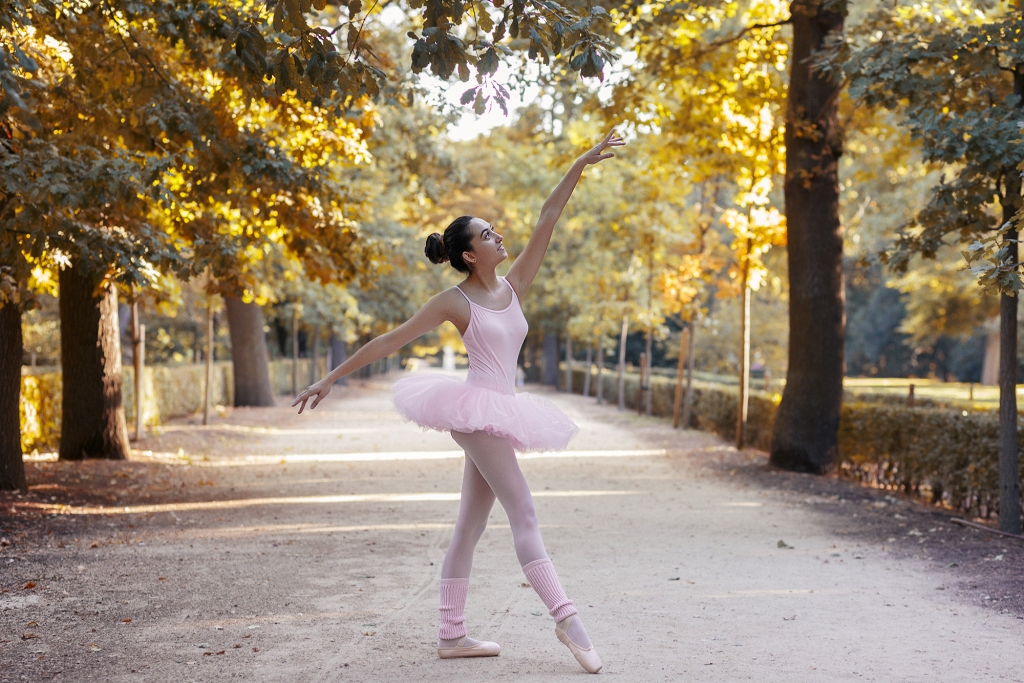 Bailarina con tutú en medio de un camino en el parque.