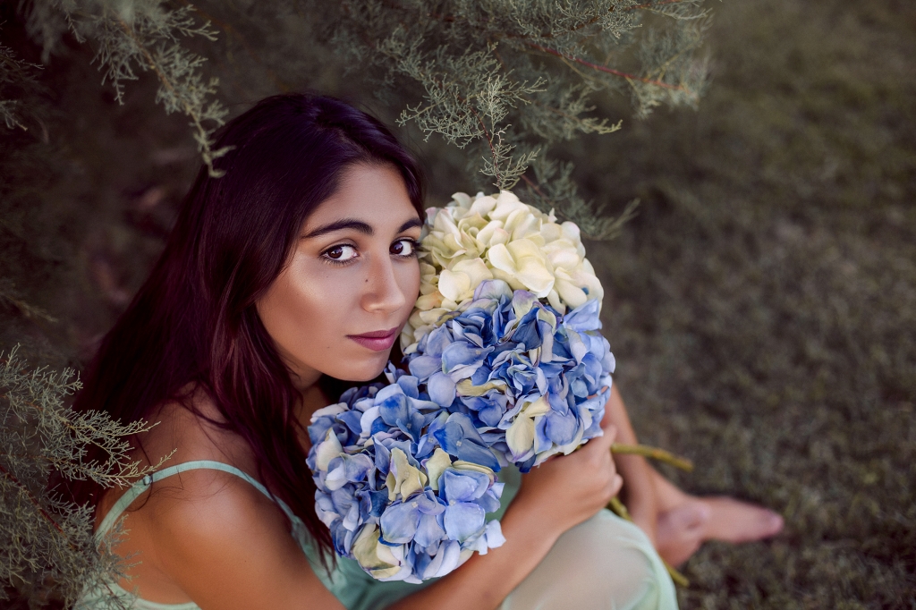 Retrato de chica con ramo de hortensias azules.
