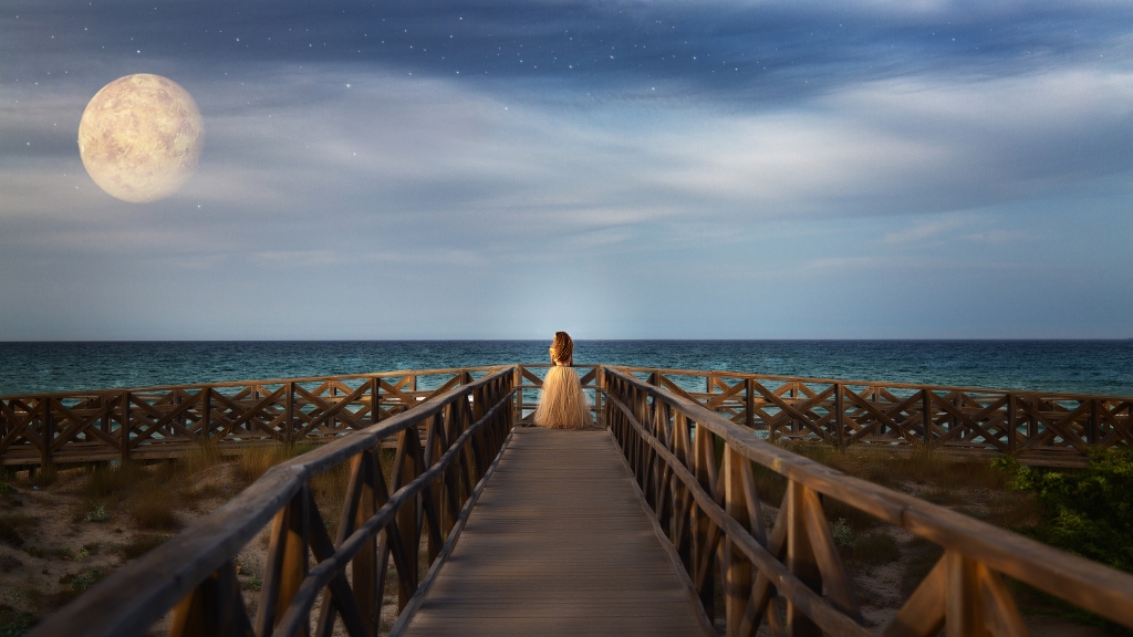 Mujer al final de una pasarela de madera, mirando al mar y a Venus.