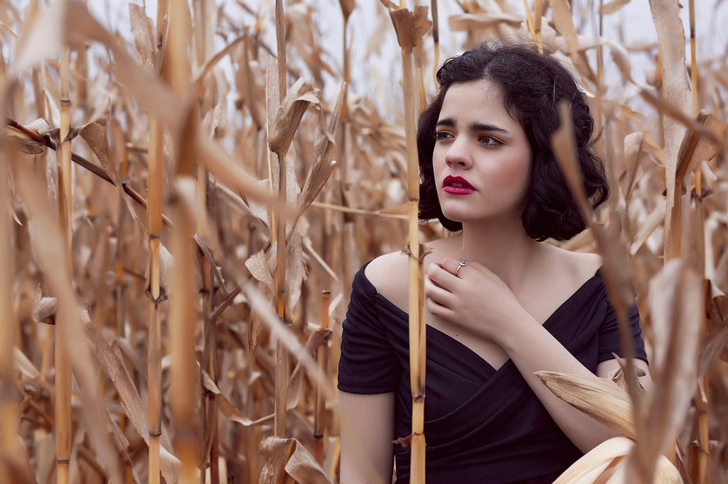 Chica vestida de negro dentro de un campo de maíz.
