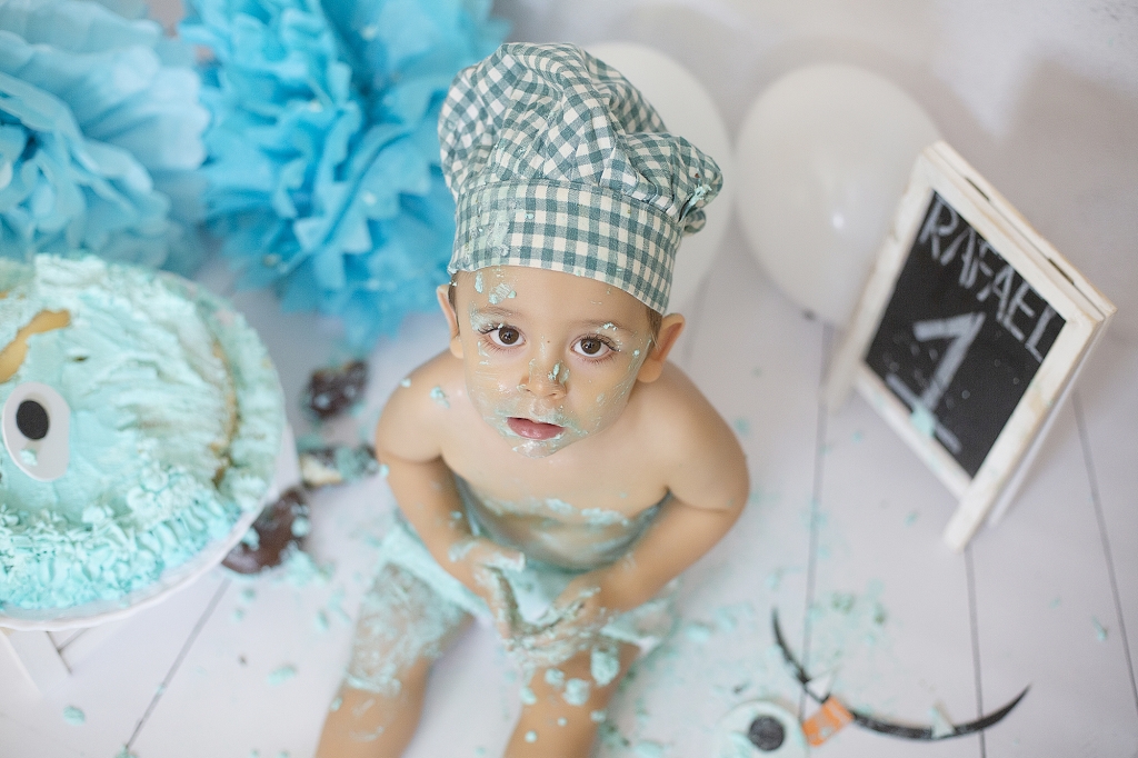 Niño con gorro de cocinero en su primer cumpleaños con banderines, globo y tarta.