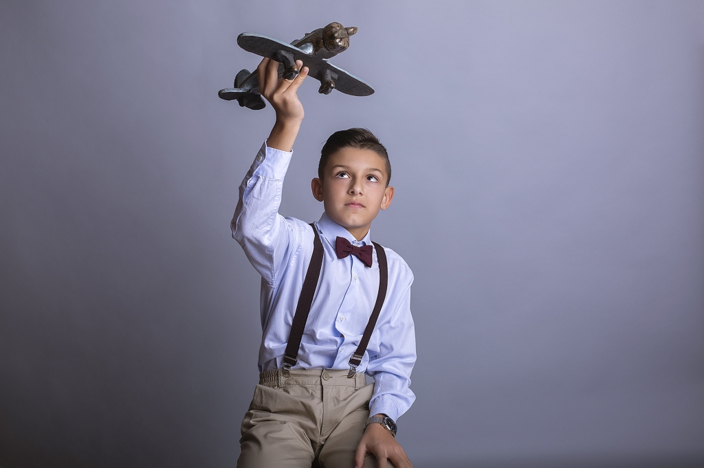 Niño de Comunión volando un avión de juguete.