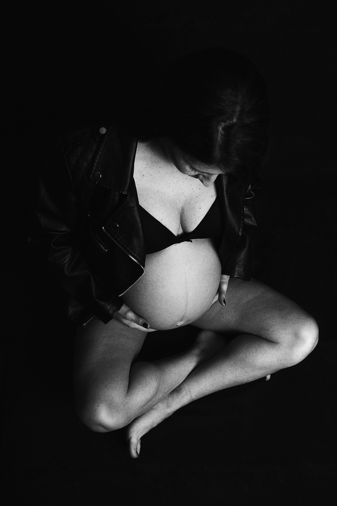Embarazada en el suelo en blanco y negro con cazadora de cuero.
