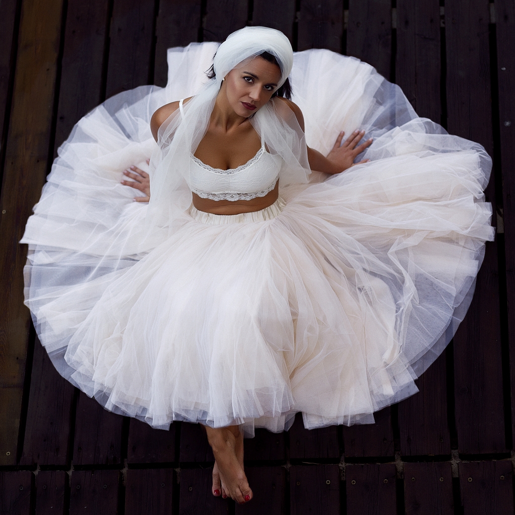 Bailarina con tutú blanco sentada sobre un suelo de madera oscura.