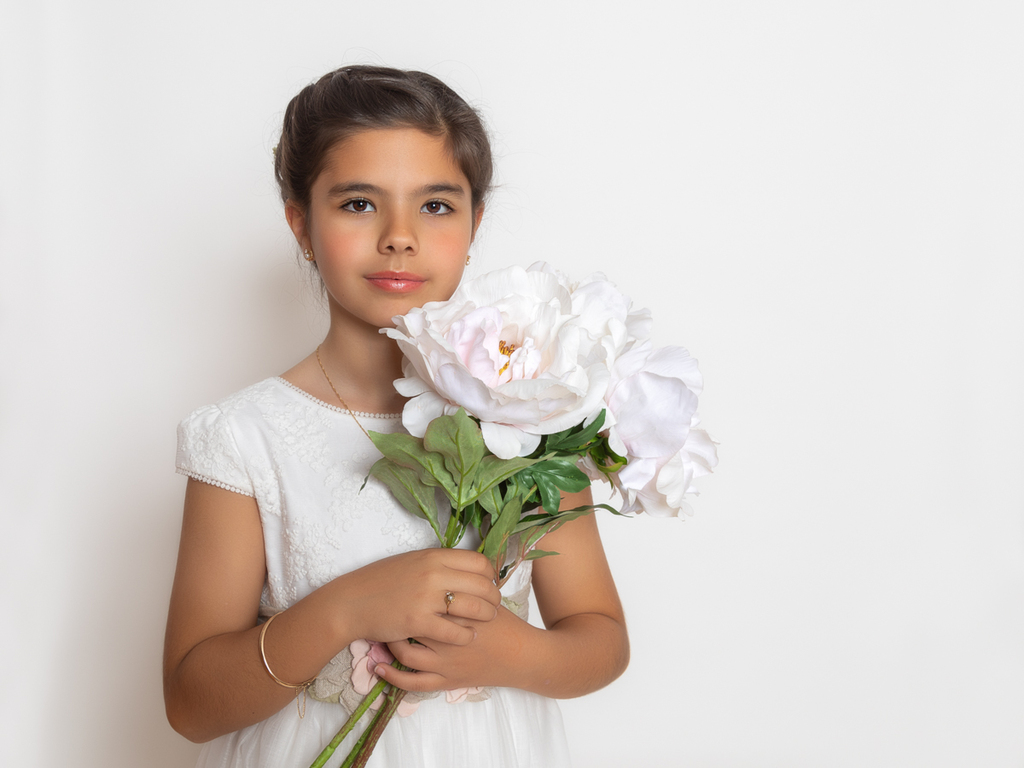 Retrato de niña de Comunión con ramo de flores blancas.