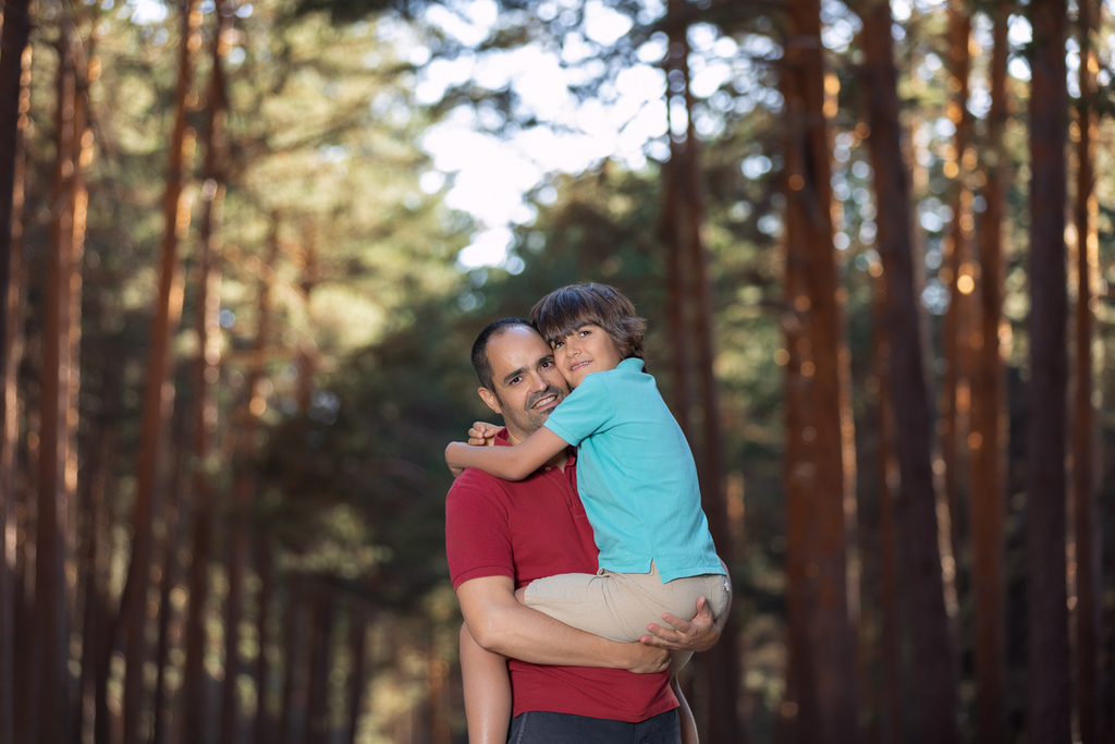Padre e hijo abrazados en una camino en el bosque.