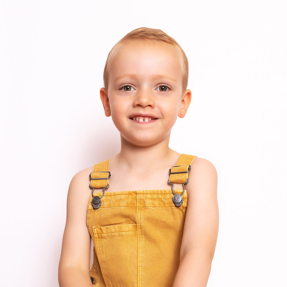 Niño sonriente con un pantalón amarillo.